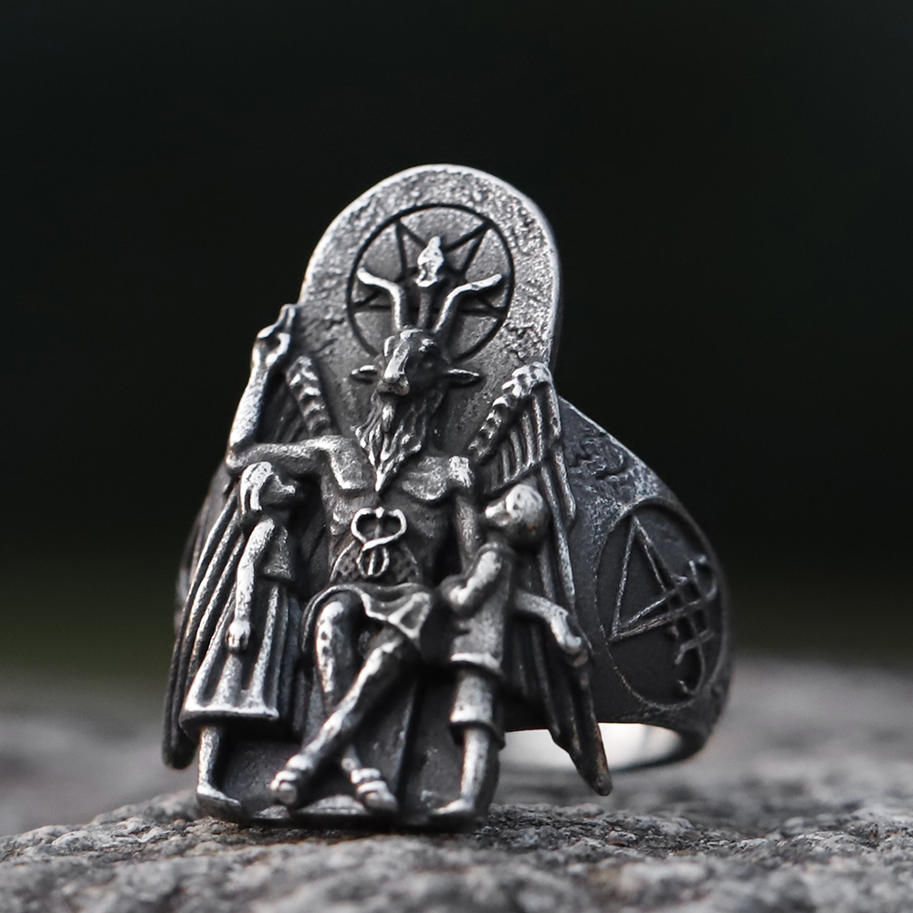 Intricate carving of Baphomet and two figures on a stainless steel men's ring, close-up.