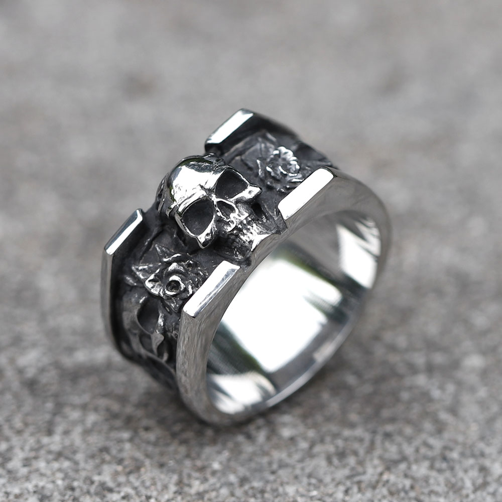 Men's 316L stainless steel vintage skull ring, featuring a prominent skull and side engravings, displayed on a concrete surface.