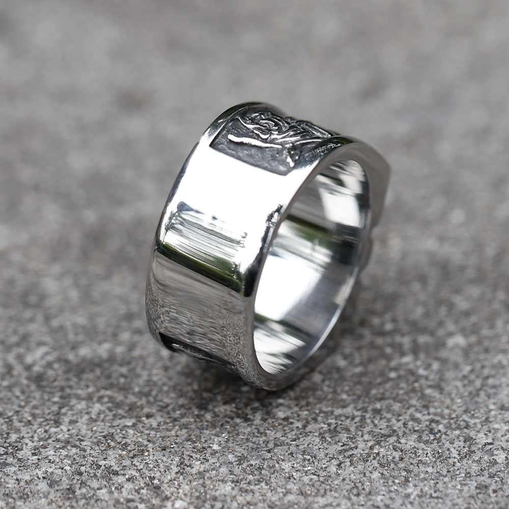 Detailed view of the side engraving, including a rose and abstract pattern, on the left side of the stainless steel skull ring band.