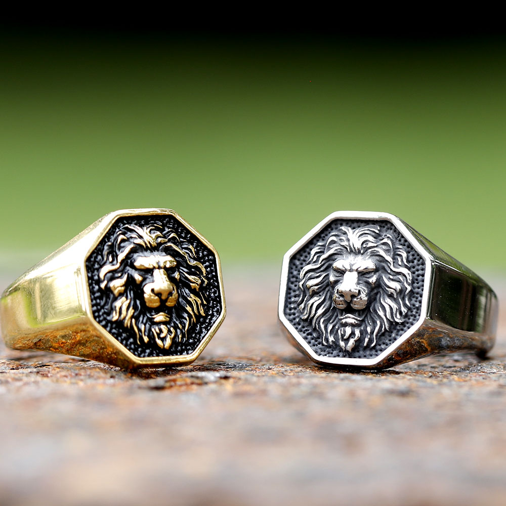 The bold stainless steel lion head ring positioned on a weathered, dark background for contrast.