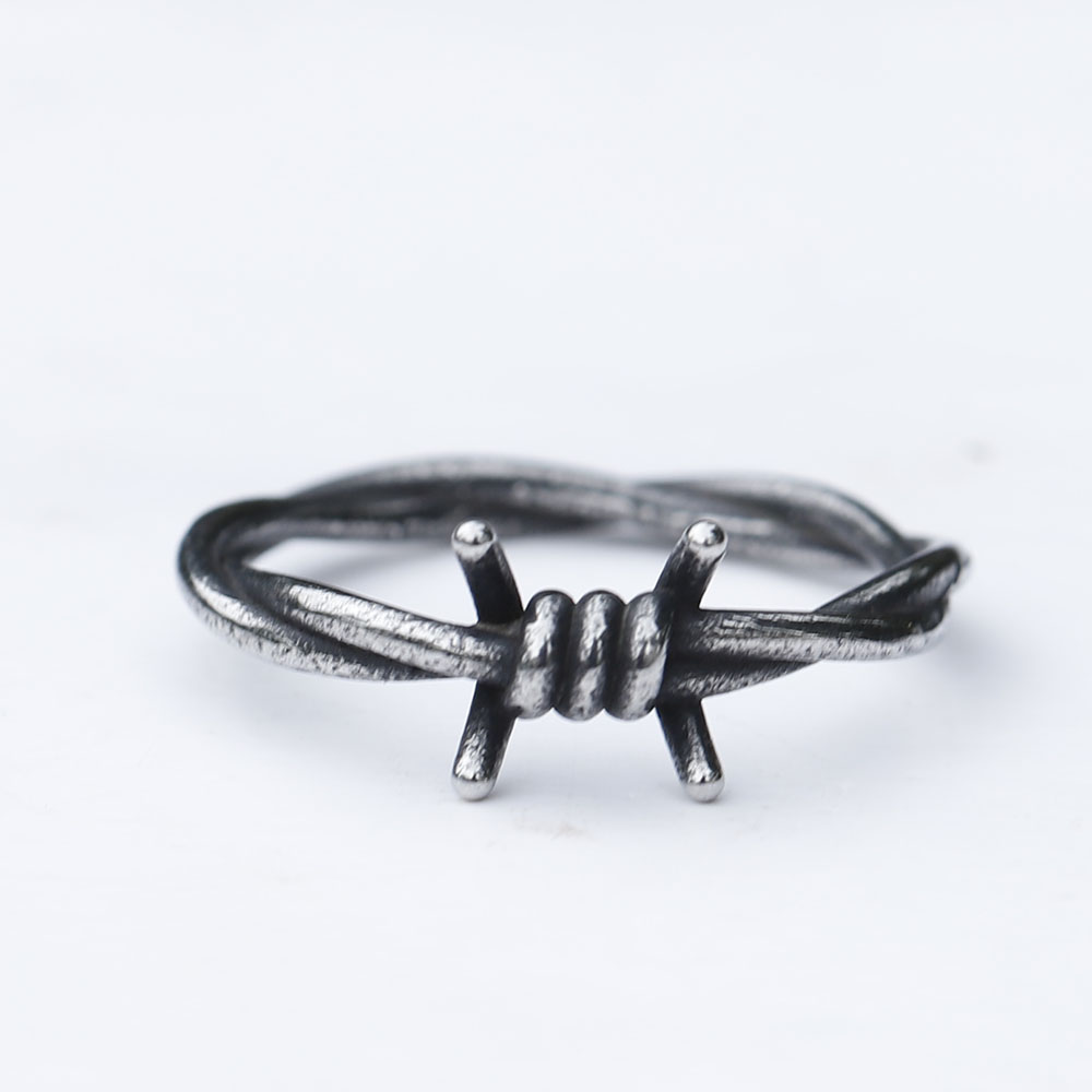 Close-up of a rustic 316L stainless steel barbed wire ring on a white background.