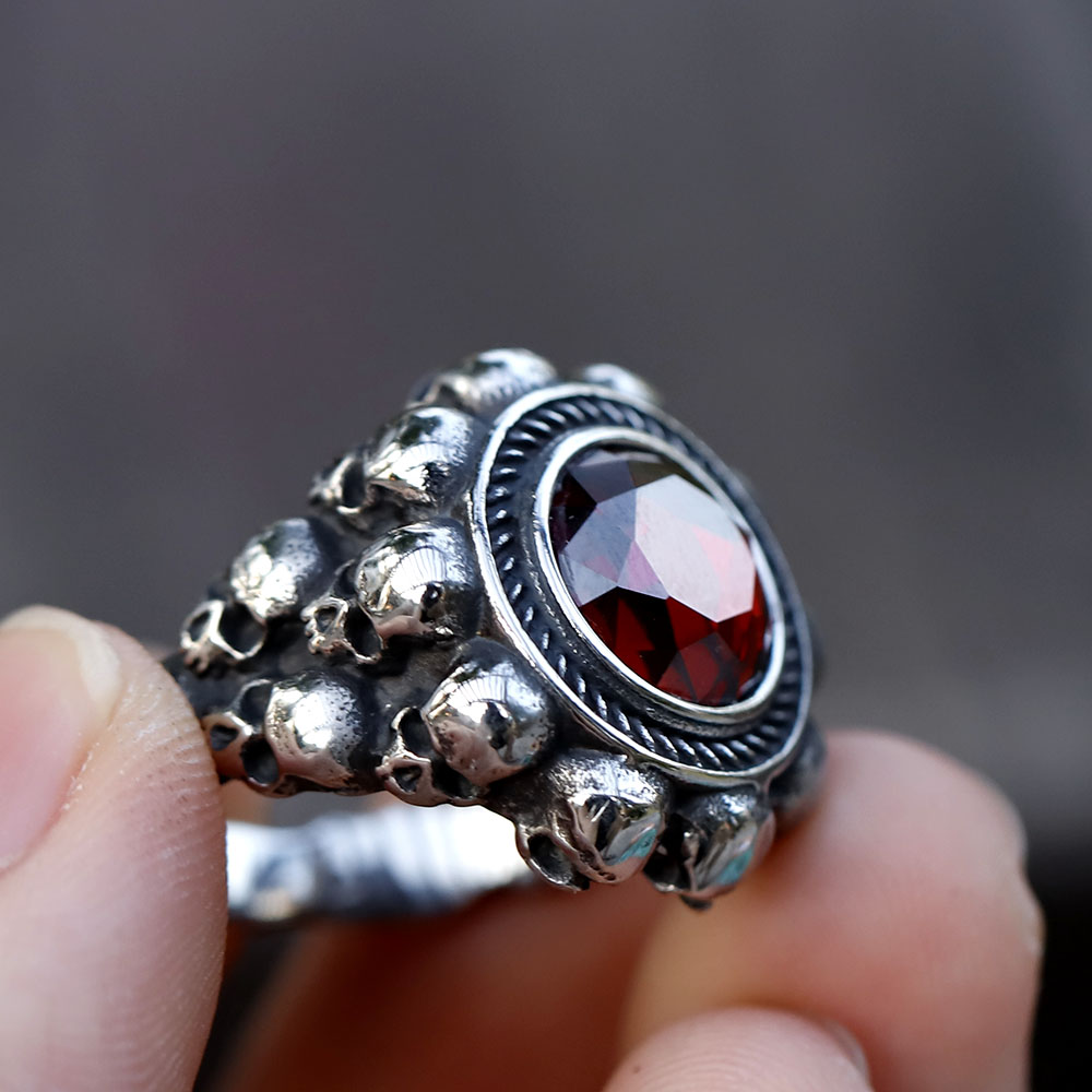 Angled perspective of the vintage punk ring, emphasizing the contrast between the steel skulls and the red zircon.