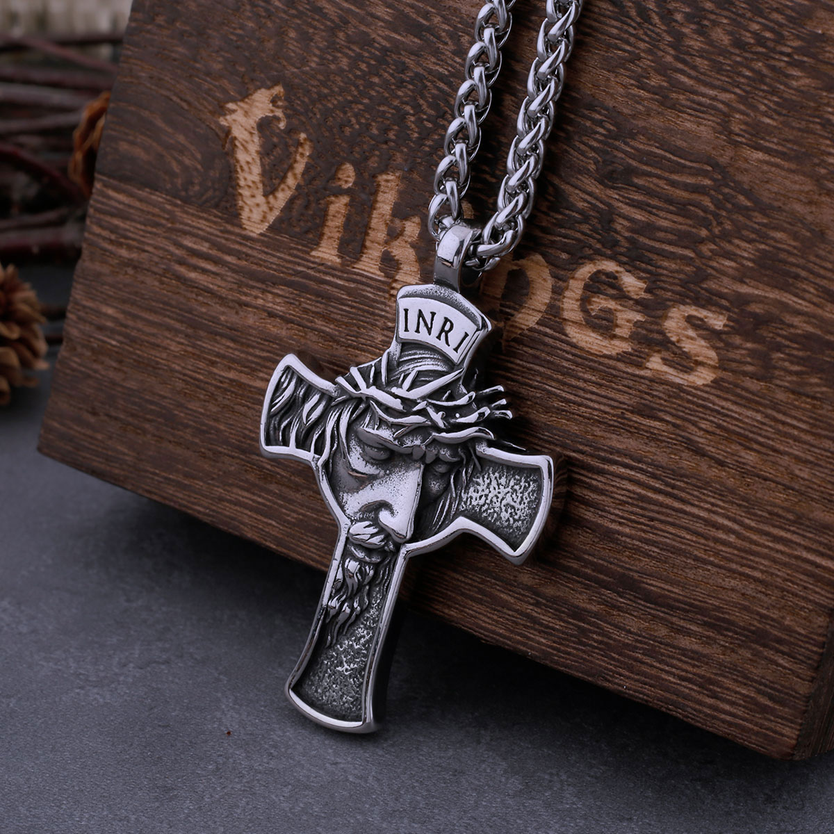 Stainless steel Jesus cross pendant and chain, showcasing the sturdy link design, partially in a wooden box.