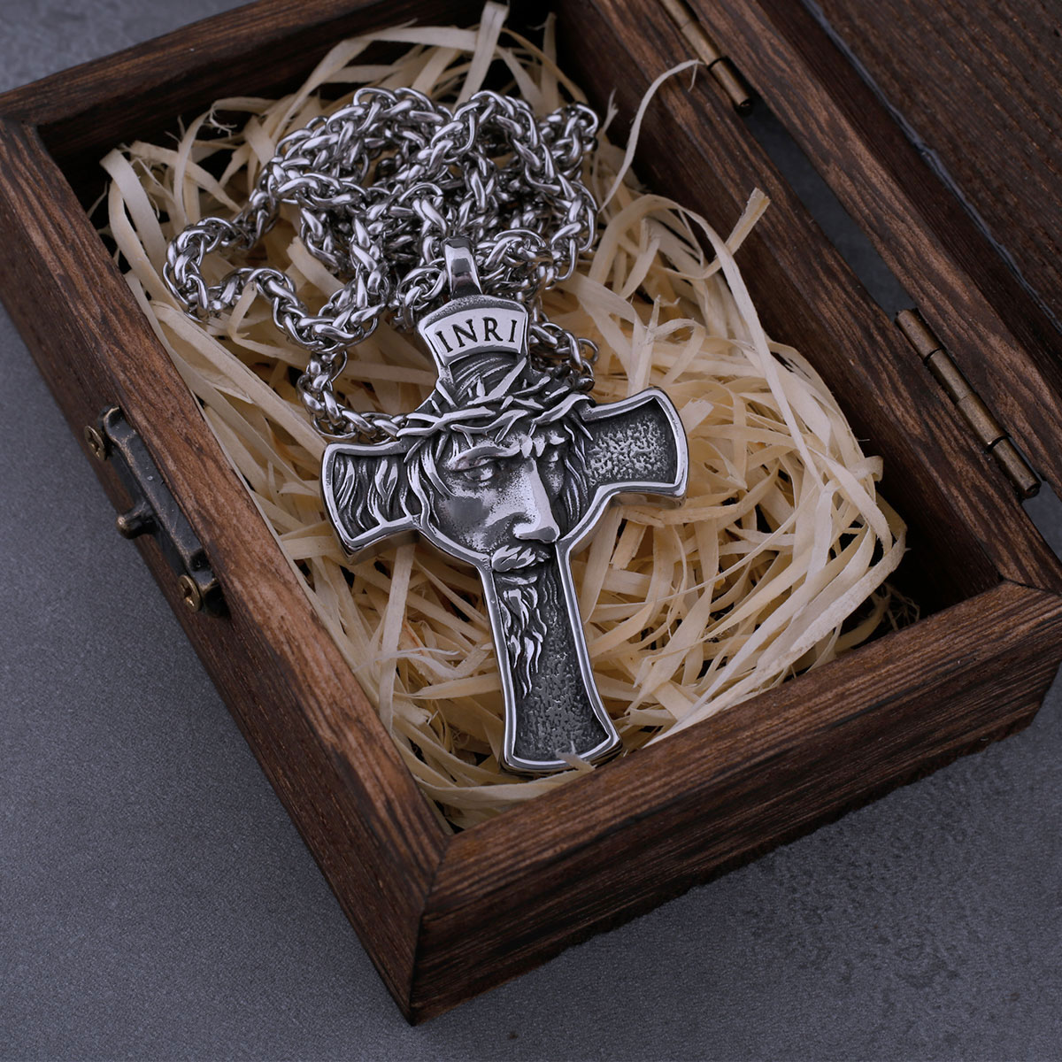 Close-up profile of the finely detailed Jesus face and crown of thorns on the stainless steel cross pendant.