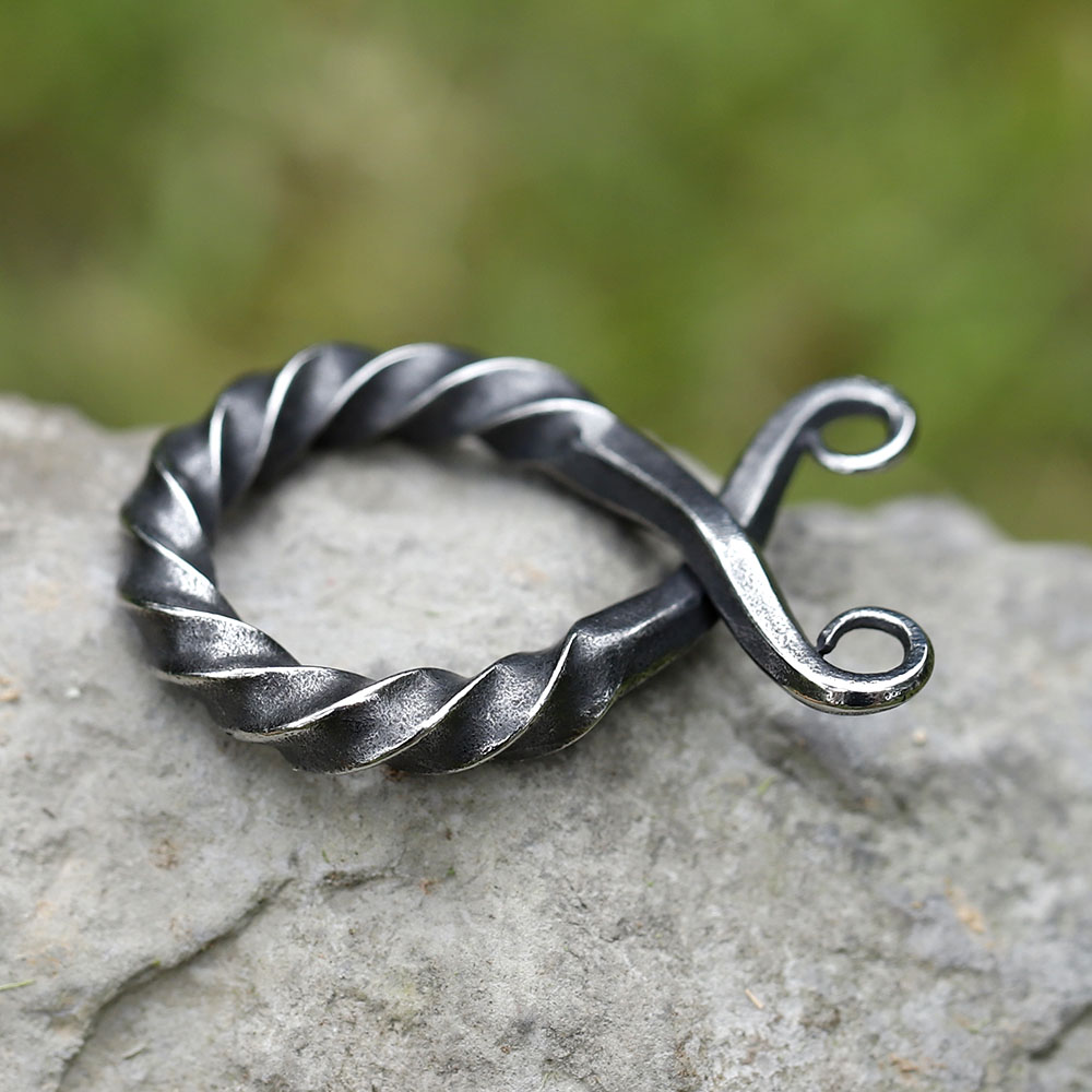 Bottom curled end of the vintage Viking amulet against a natural stone background