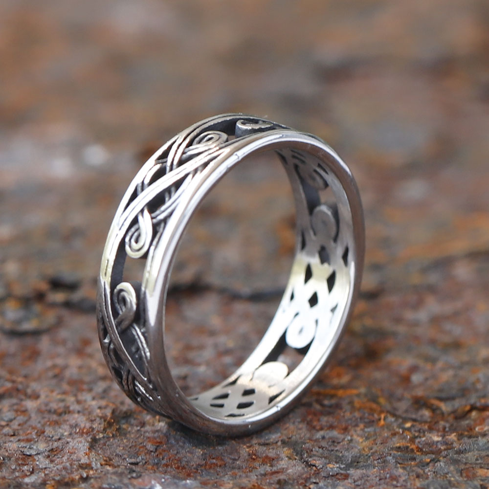 Stainless steel Celtic knot openwork ring displayed on a rustic metal surface