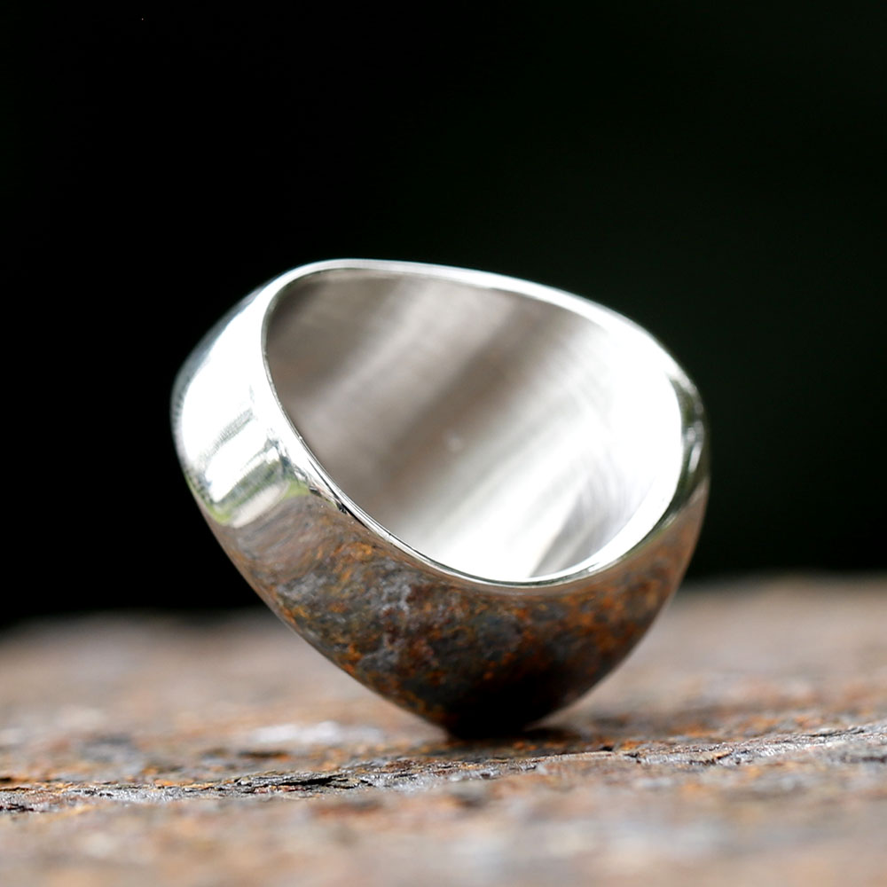 Detailed shot of the textured background surrounding the Mythosaur skull on the ring's face.