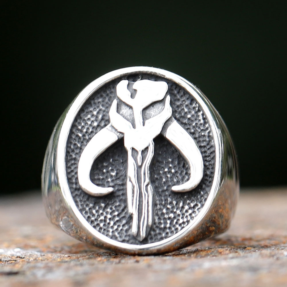 Full view of the stainless steel Mandalorian Mythosaur skull signet ring on a rustic surface.