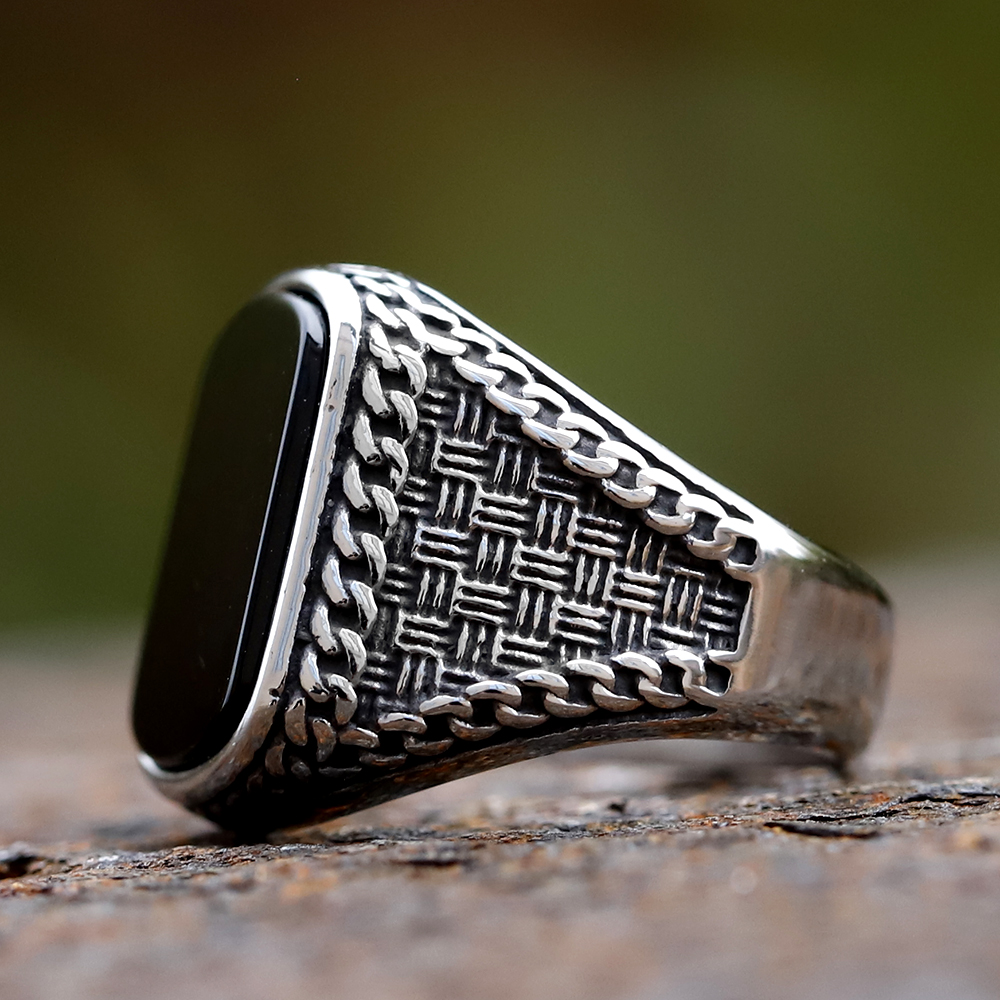 Detail of the intricate woven and chain-link texture on the band of the men's ring.