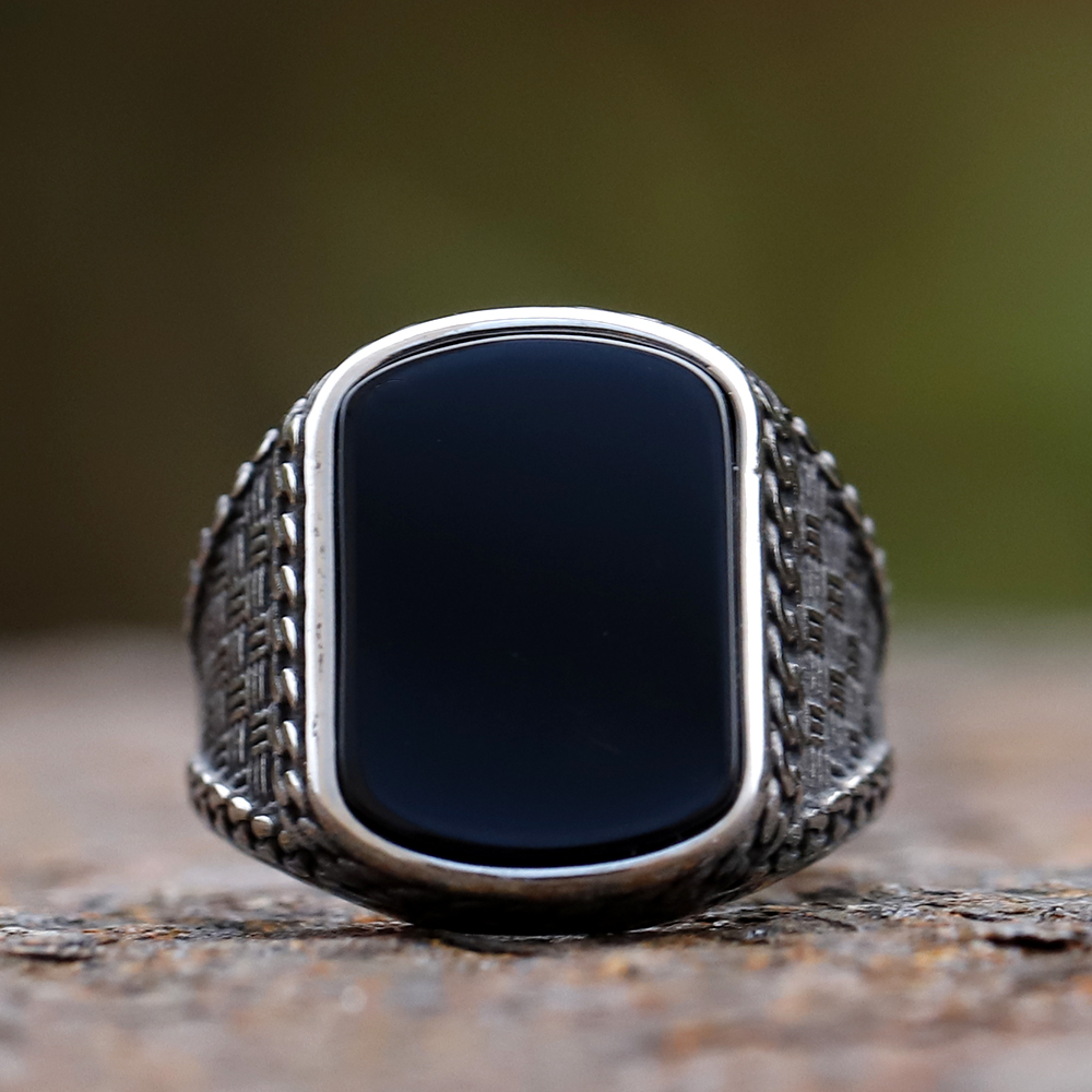 Angled shot of the punk-style men's ring with a prominent, polished black stone.
