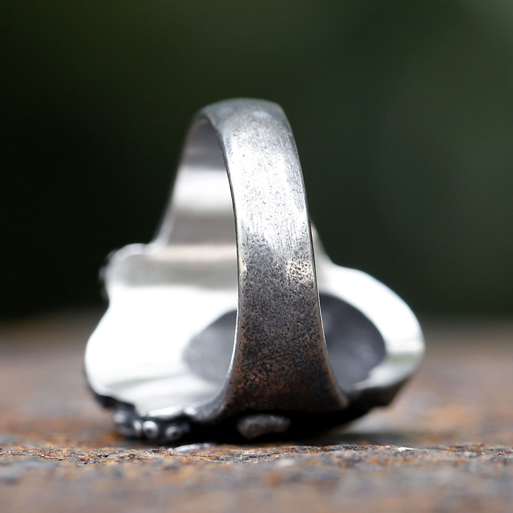 Angled shot showcasing the robust stainless steel band and the overall punk aesthetic of the ring.