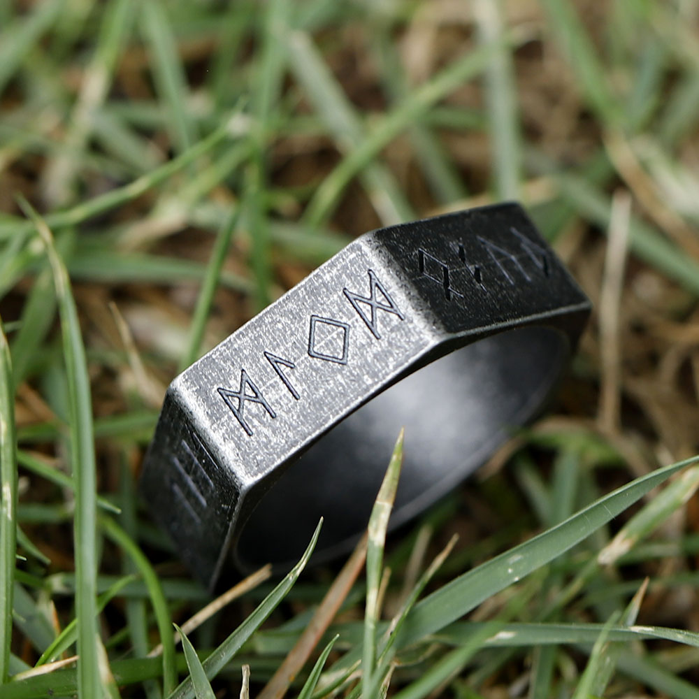 View of the stainless steel hexagon ring from a slight angle, focusing on the robust metal and carved runes.