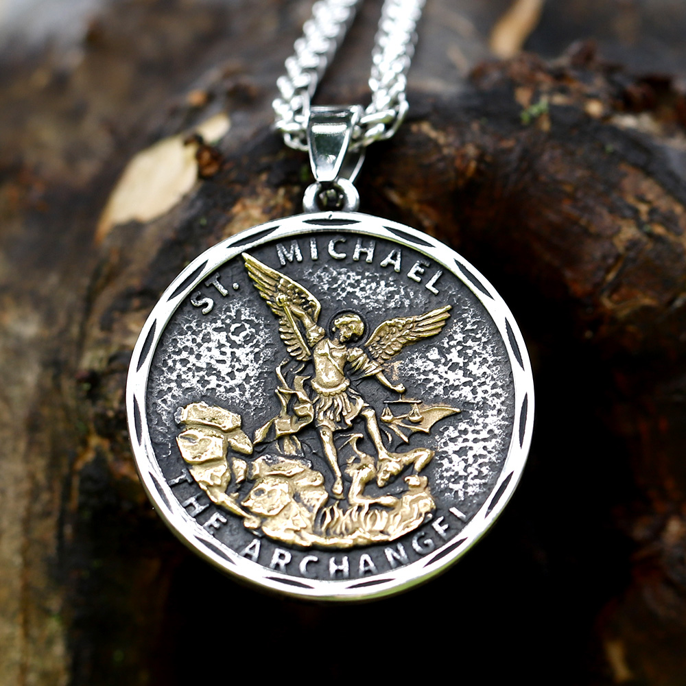 Close-up of the top right of the St. Michael pendant and chain on a textured surface.