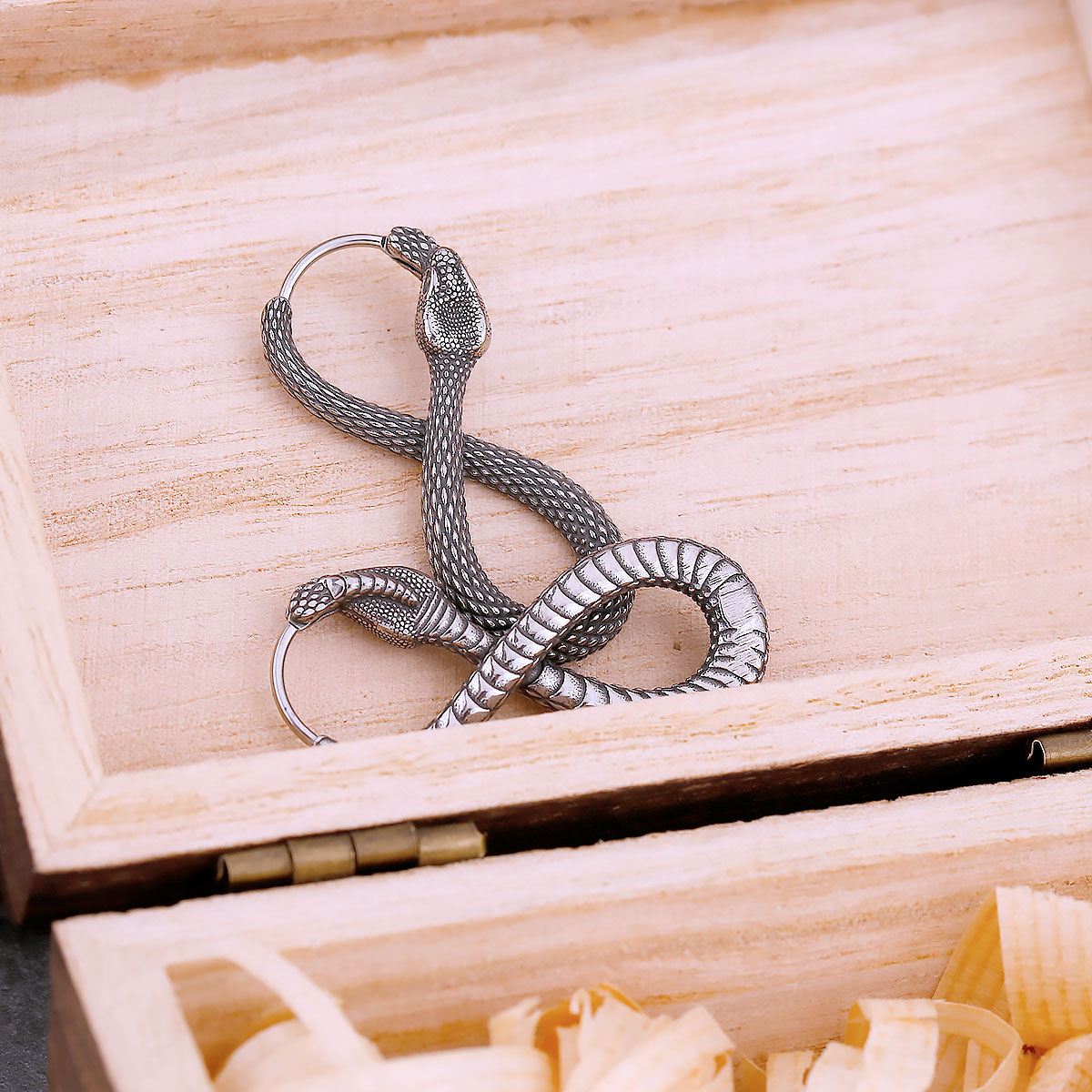 Close-up of the right snake earring's head and hoop closure, showing intricate scale details.