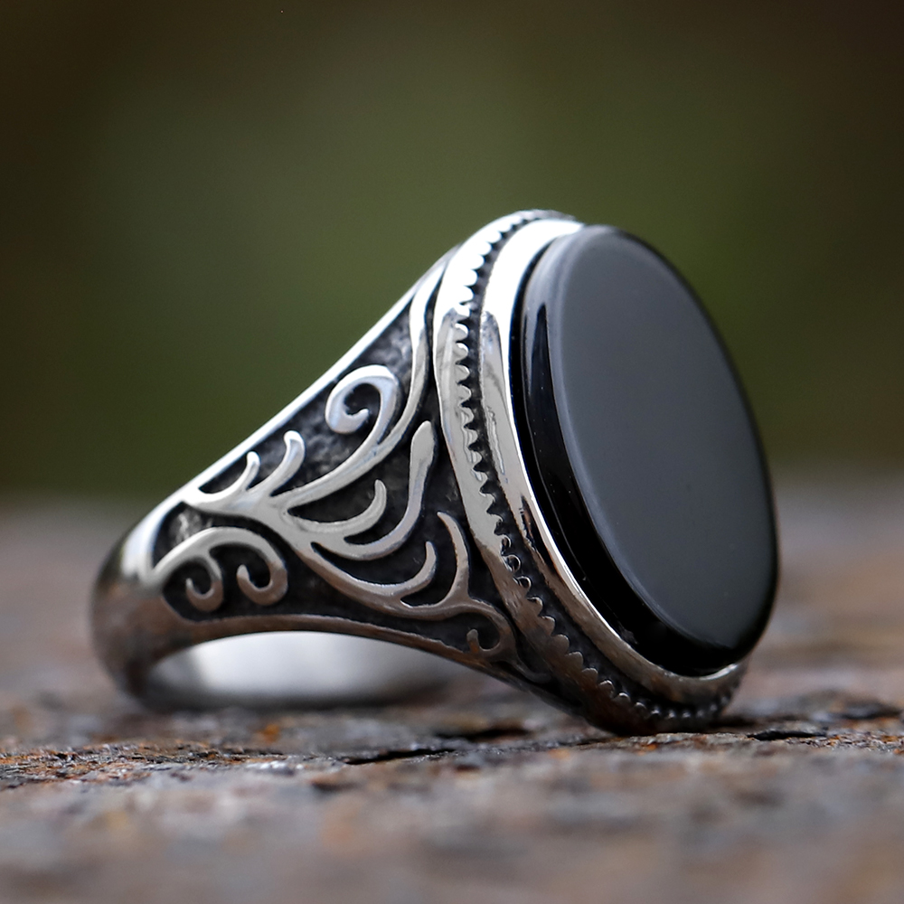Men's black stone ring worn on a finger, showcasing its scale and fit with an outfit