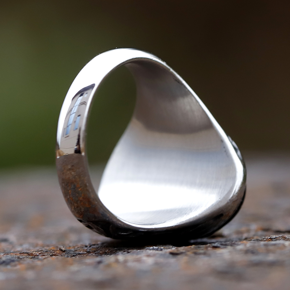 Detailed shot showing the textured silver band and carving on the men's retro ring