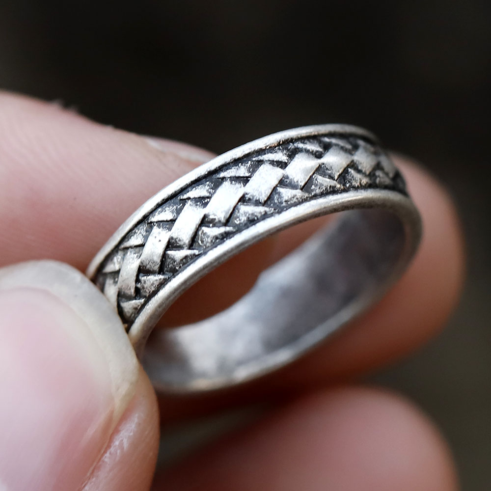 Close-up showing the full width of the braided men's stainless steel ring resting on a stone